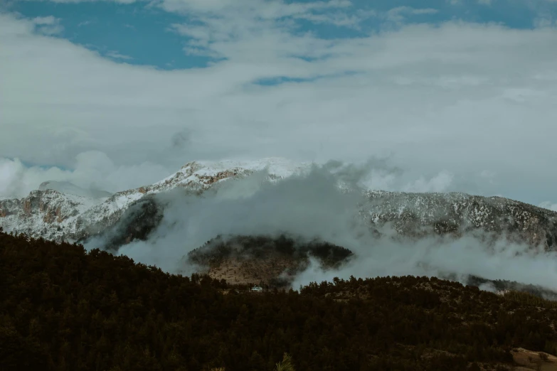 a few clouds on top of mountains in the wilderness