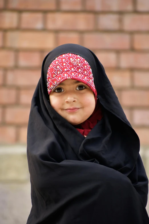 a child wearing a scarf is smiling while posing