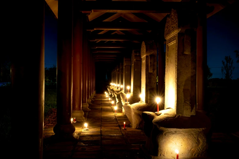 candles are lit up along the columns of an outdoor walkway