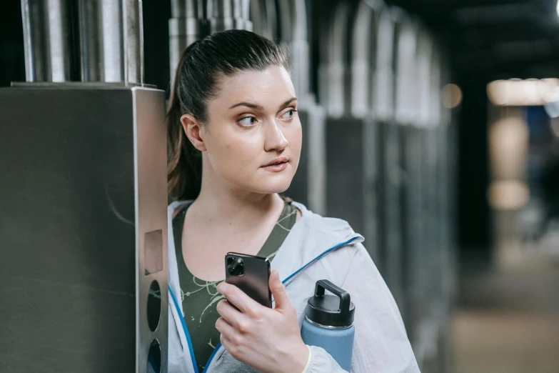 a woman leaning against a wall with a cell phone