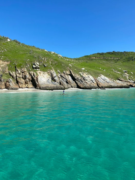 a man is kayaking into the ocean near rocky coastline