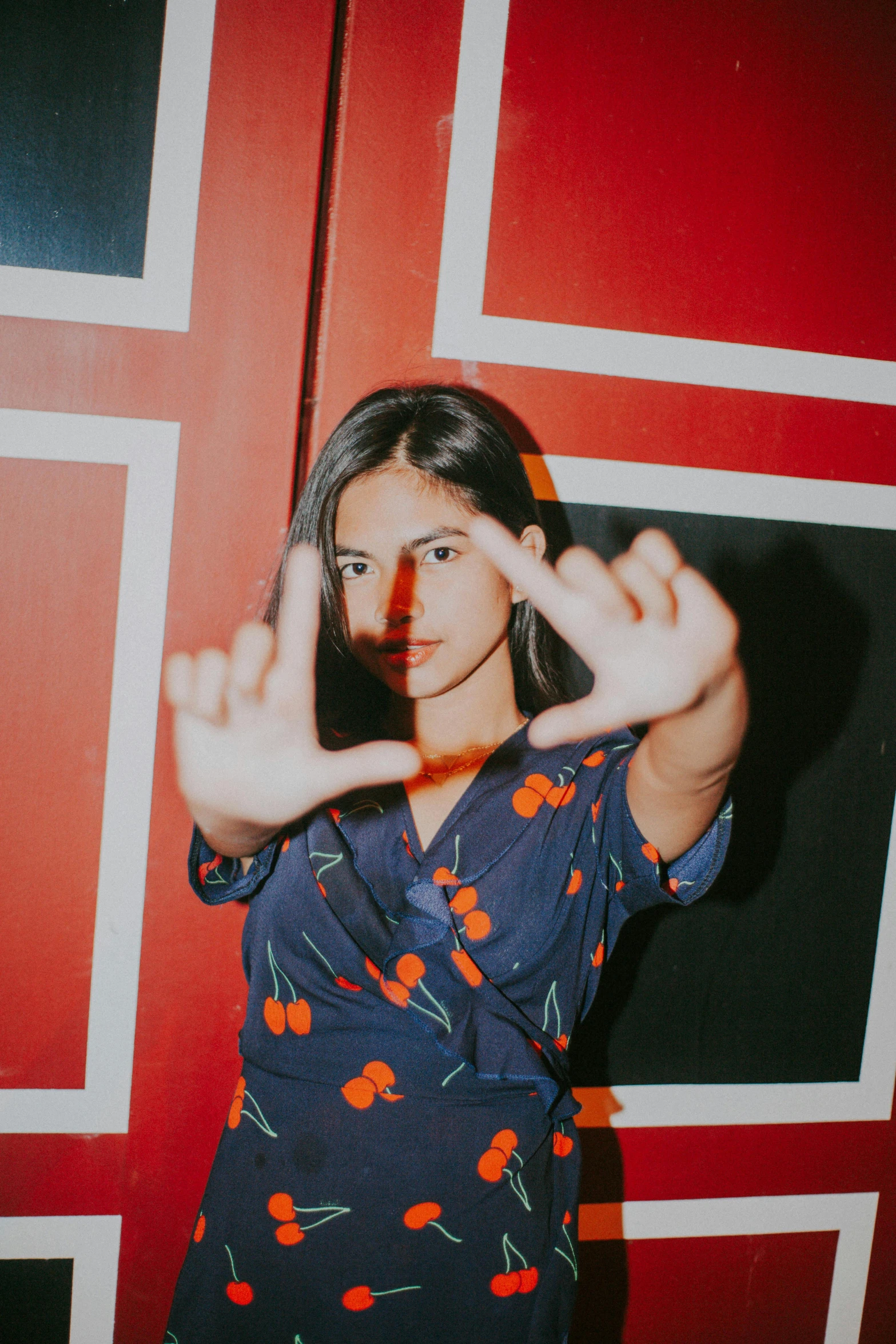 a woman making an open sign near a red wall