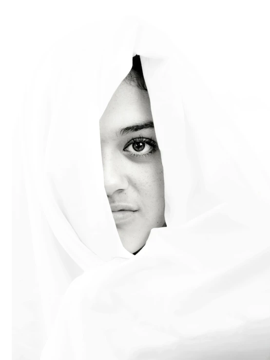 black and white pograph of woman peeking out from her blanket