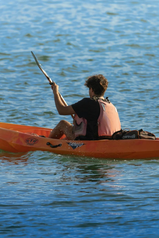 two people sitting in an orange canoe paddling on water