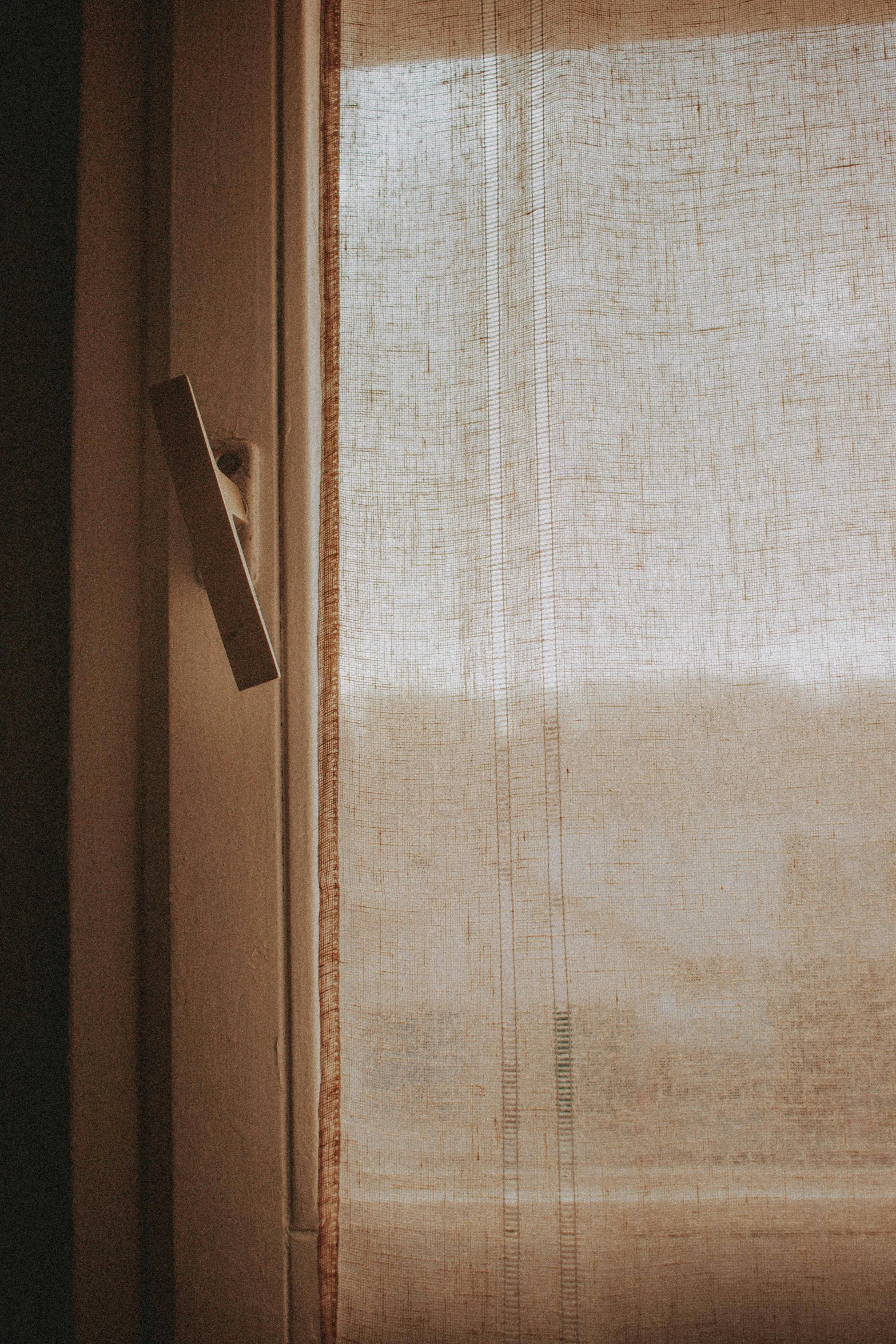 an old curtain partially ds onto a window