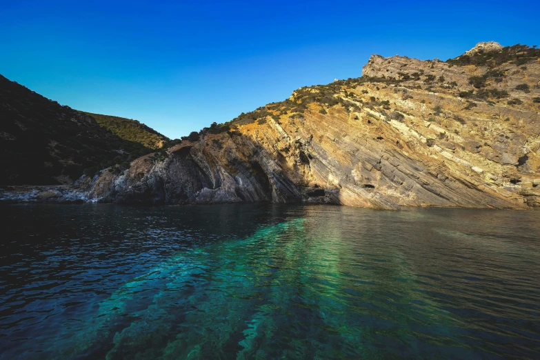 the sun shines on the steep cliffs above a body of water