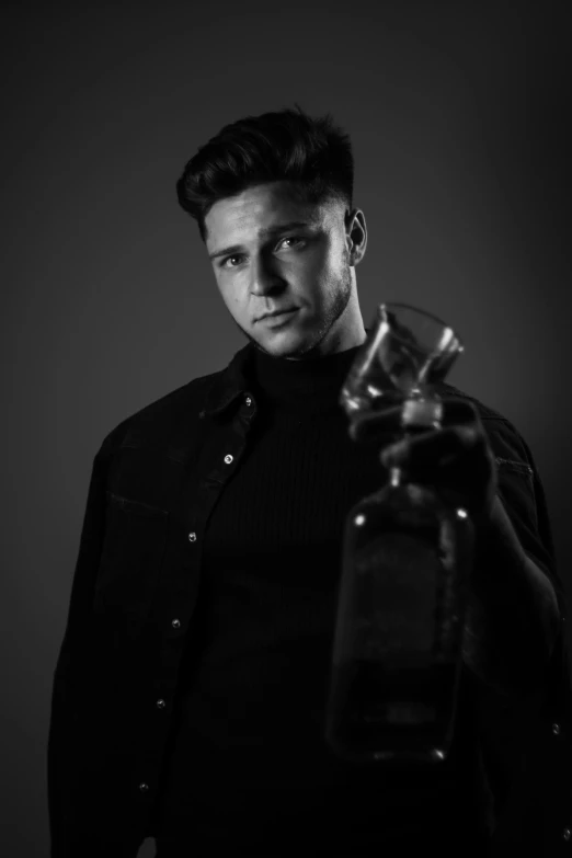 a man that is holding a bottle and posing