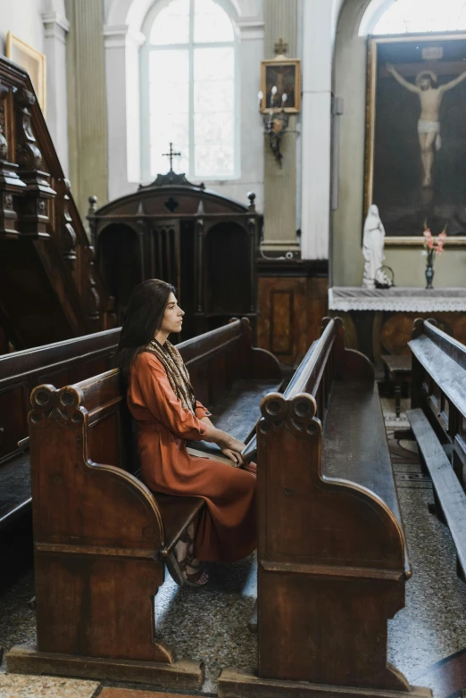 a woman sitting in an ornate room near a crucifix