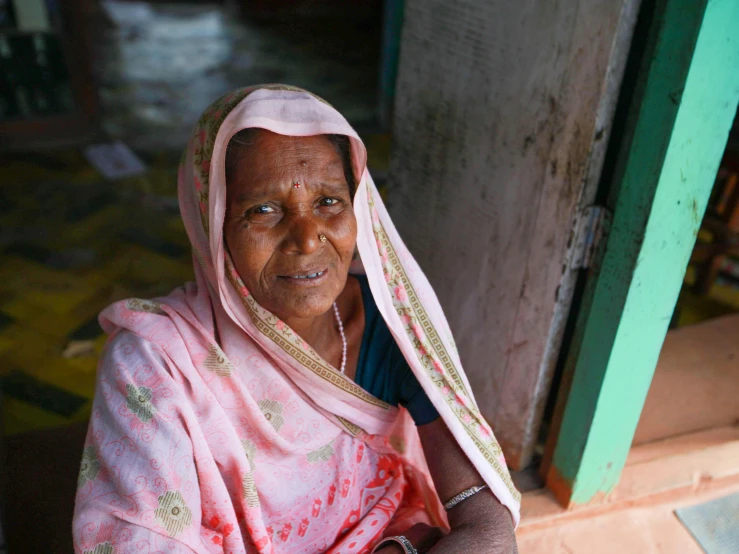 a woman with a pink scarf around her head sitting down