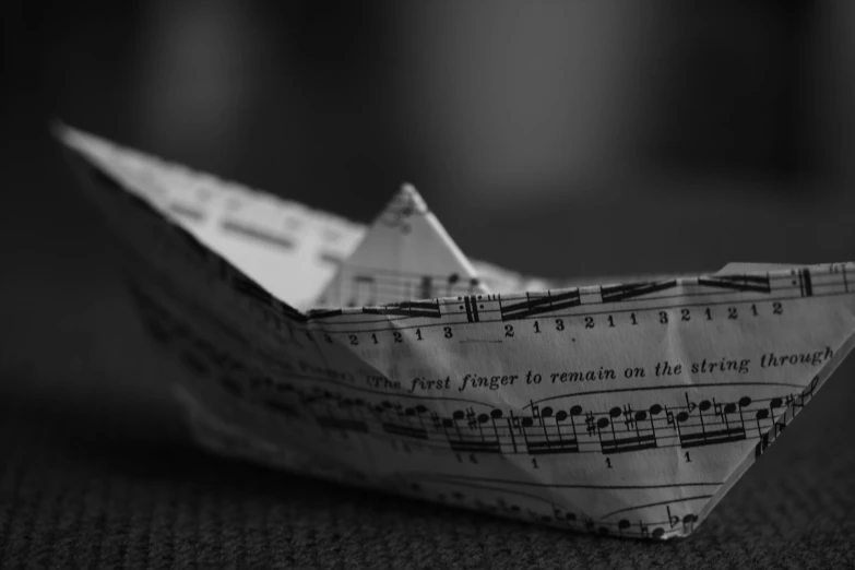 a small white origami boat with sheet music notes