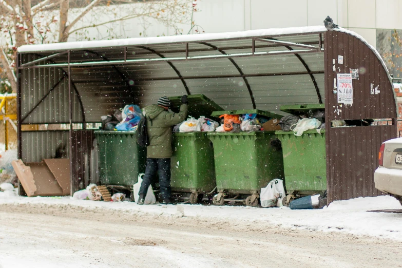 two people standing at a dumpster in the snow