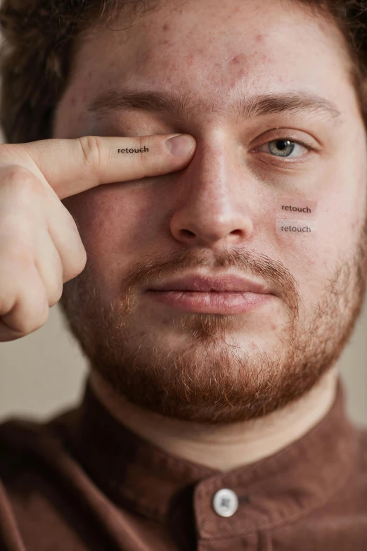 the man has a small tattoo on his forehead and has both fingers on it