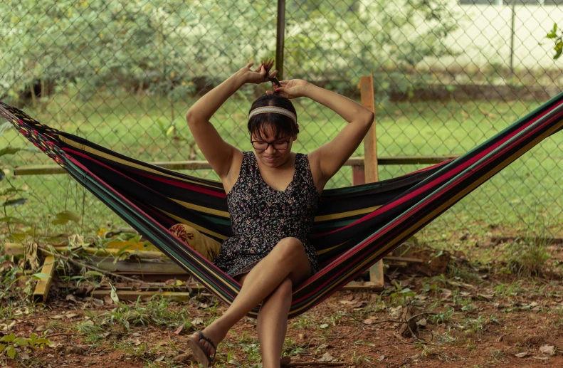 a woman in a dress holding onto a colorful hammock