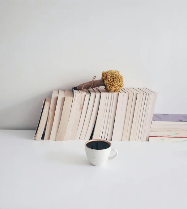 a stack of books and a cup on a white table