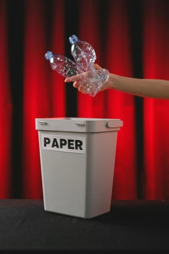 a person holding an award for excellence, and placing it inside of a paper container