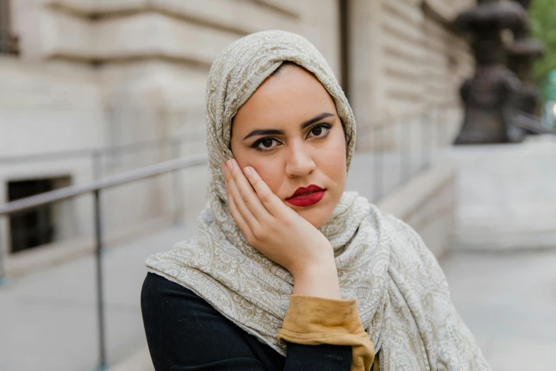 a woman wearing a scarf has her hand on her face