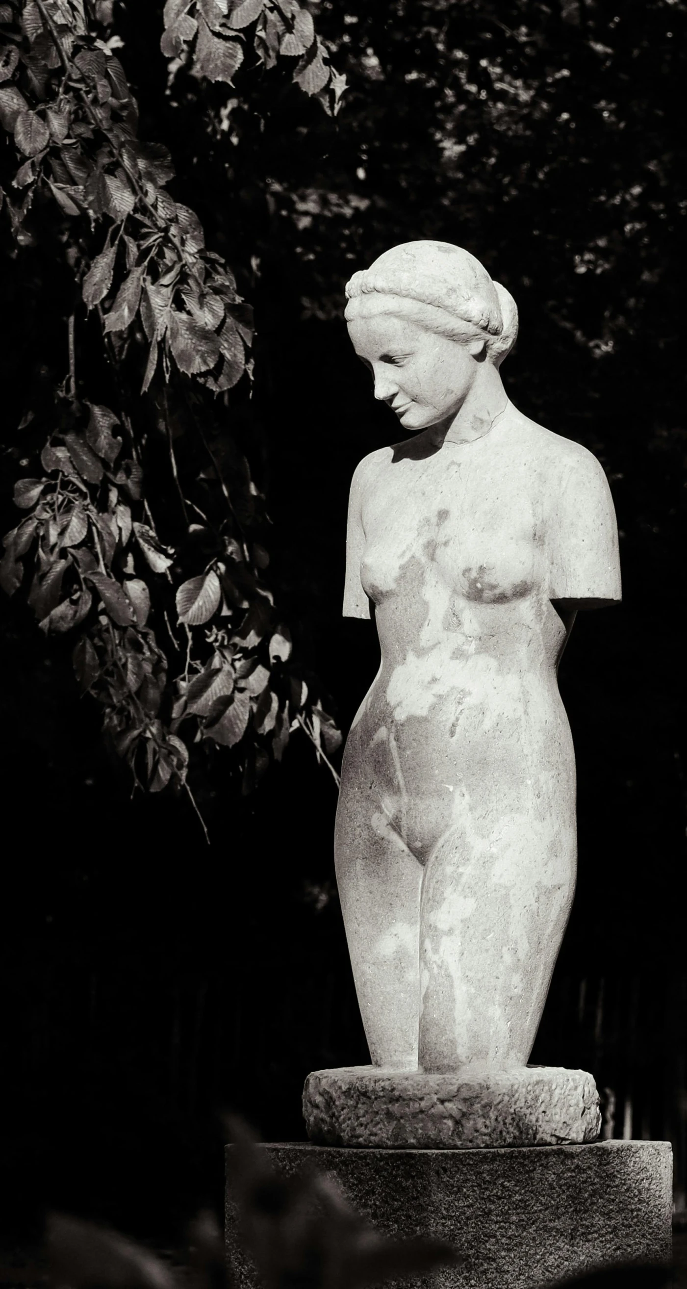 a statue of a female  standing next to trees