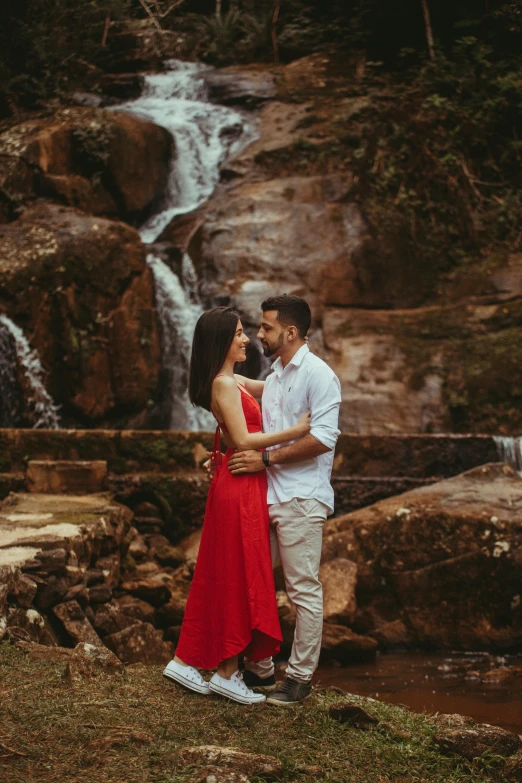 couple holding each other posing in front of a waterfall