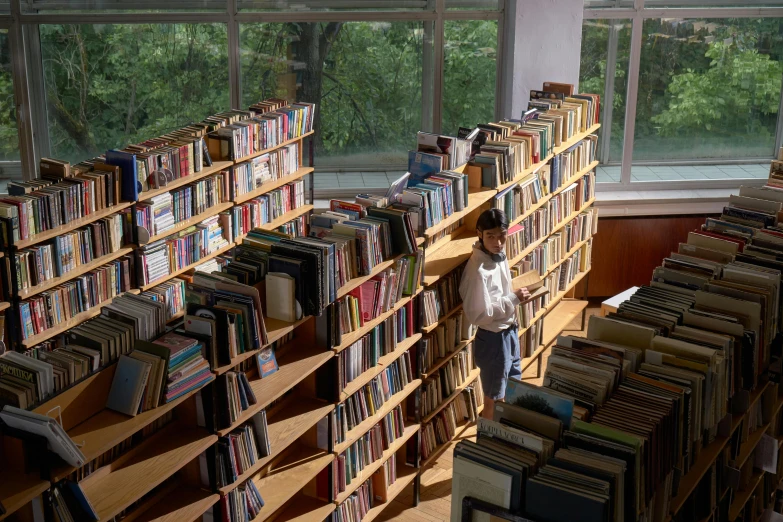 a man standing in front of stacks of books in a room