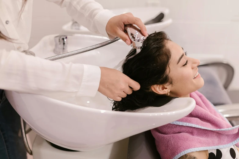 a young lady is getting her hair done by a professional