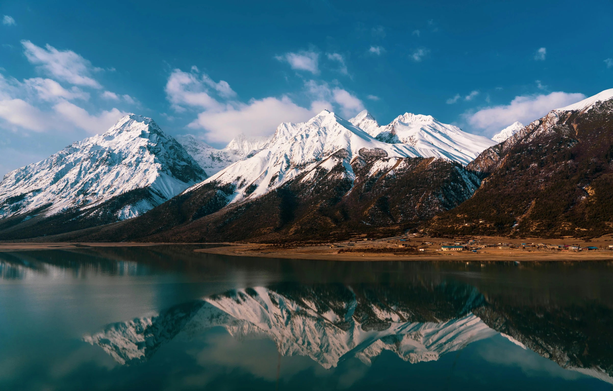 mountains with snow are shown at the base of a lake