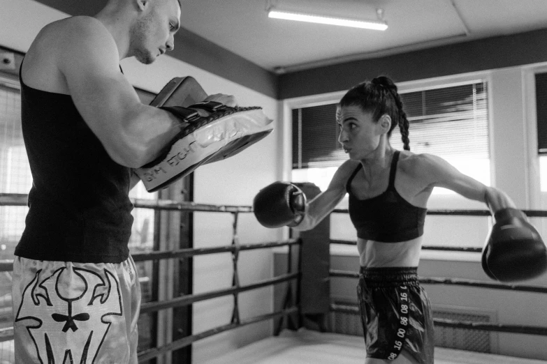 a female boxer wearing black has her gloves raised