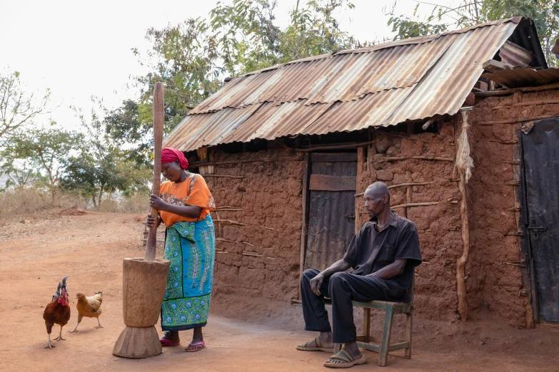 a woman standing next to a man sitting on a chair