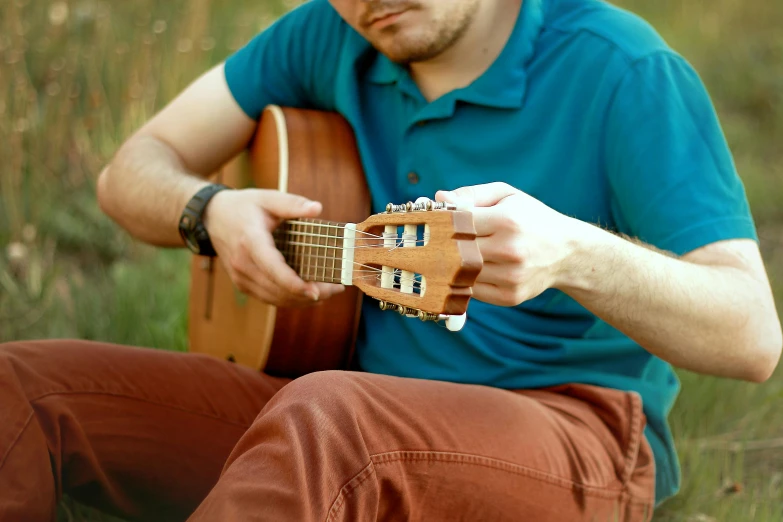 a man in a blue shirt playing an ukulele