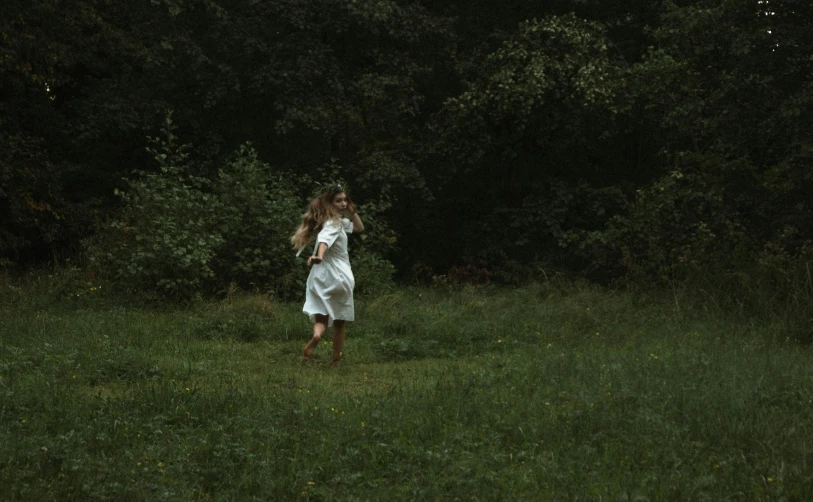 a woman is walking in the grass, with no one around her