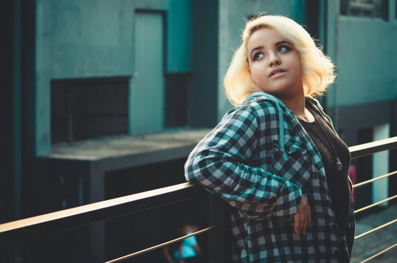 the blonde girl with a green shirt is looking out over a railing