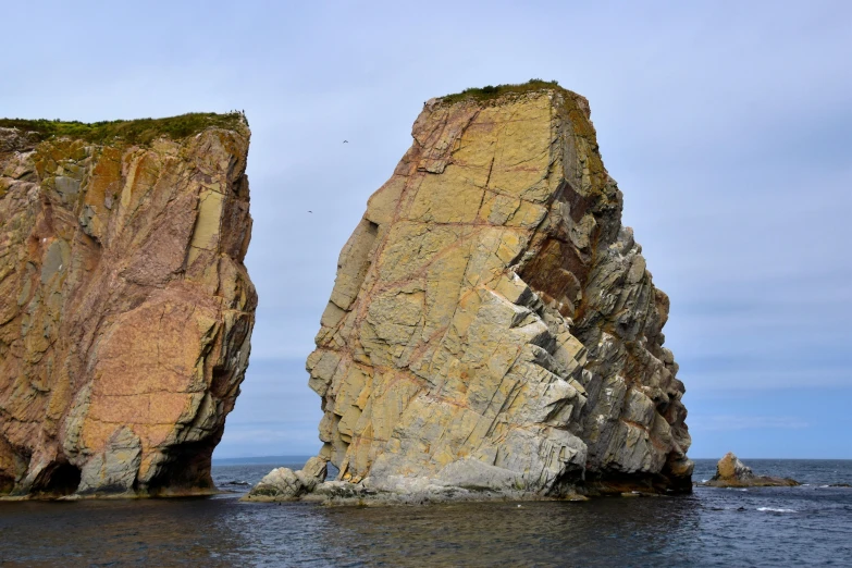 a rock formation sits between the ocean and another large rock formation