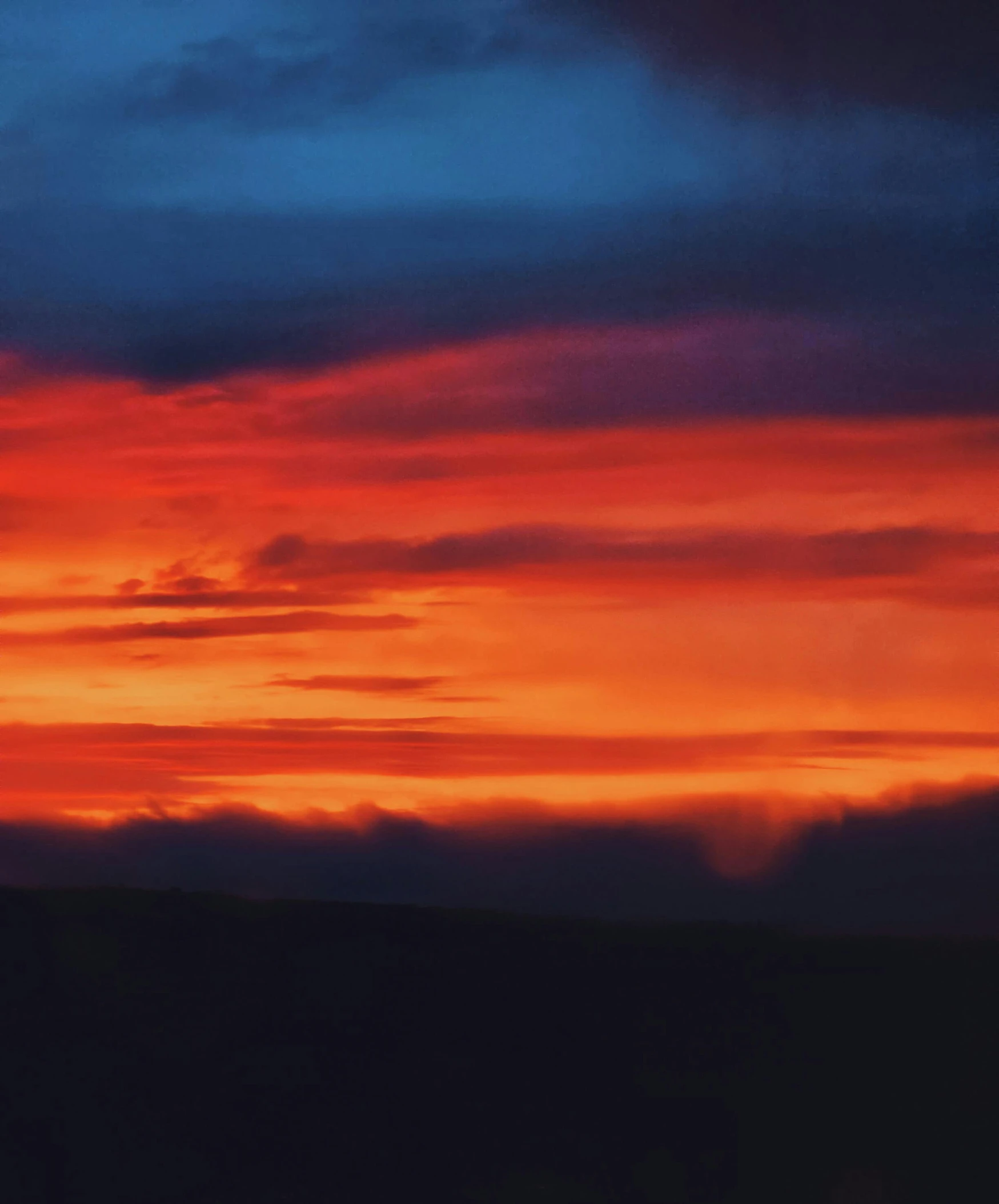 an orange and red sky over a field