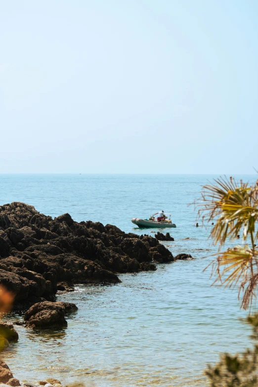 the sea and boat are sailing past some rocks