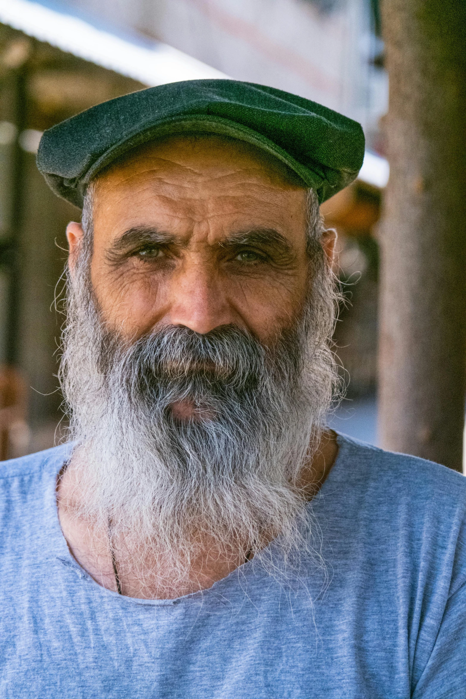 a man with a grey beard and wearing a green cap