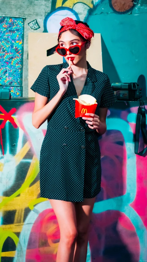 a young woman wearing glasses while holding a cup