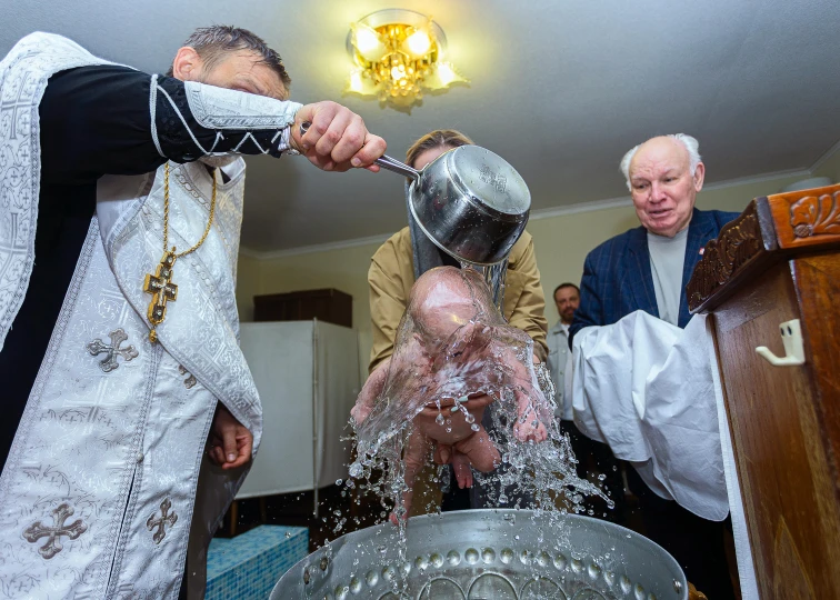 three men in traditional garb drinking water from a silver bowl