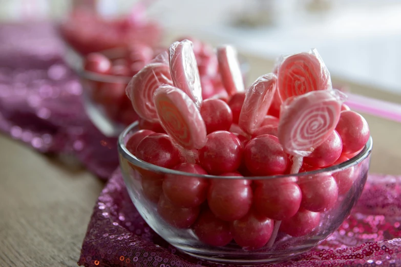 a bowl filled with pink candy lollipops