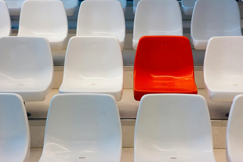 a red chair is placed in the middle of several white chairs