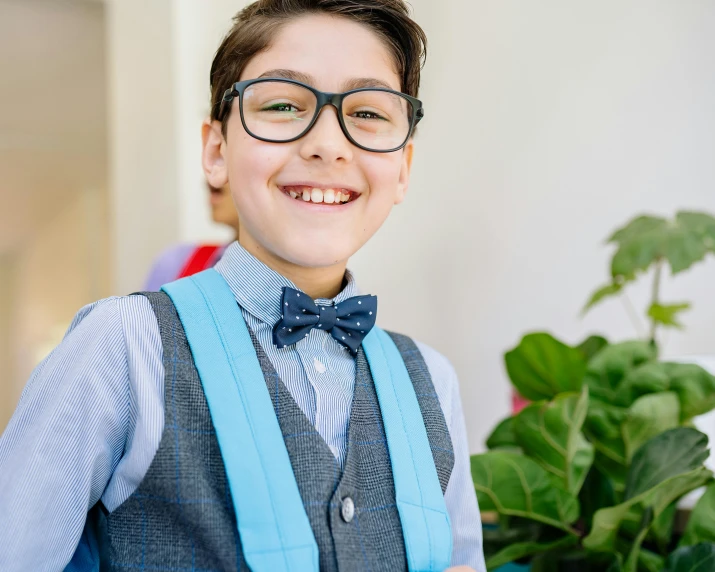 boy with glasses and bow tie smiles for the camera