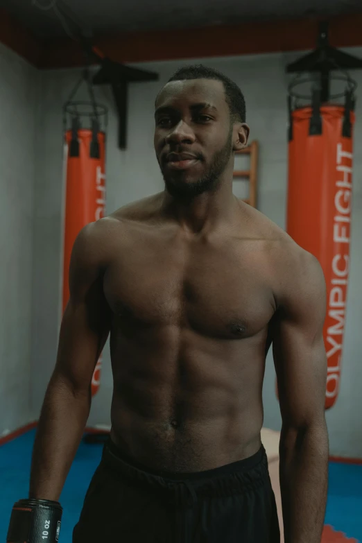 shirtless man in shorts standing by red ropes