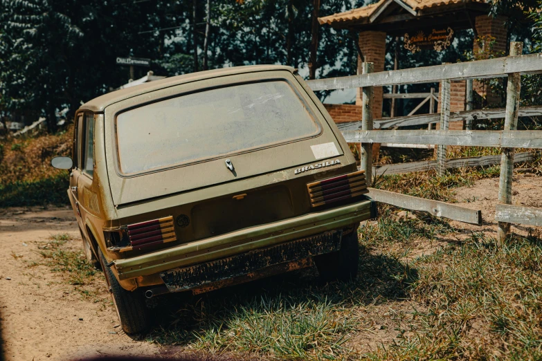 an old car parked by a wooden fence