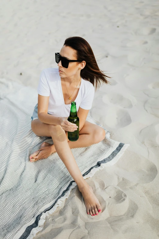 a young lady with sunglasses on sitting on the beach