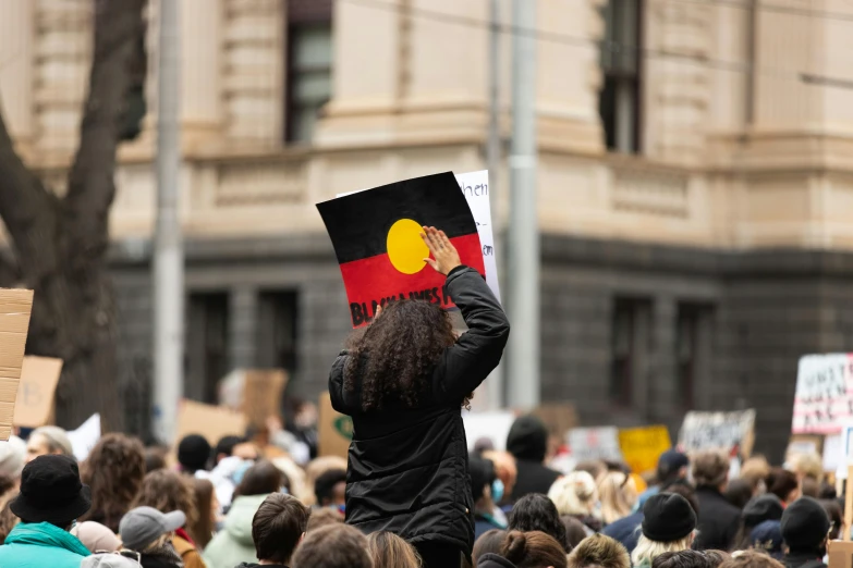 a person holding a sign with a red and yellow circle on it