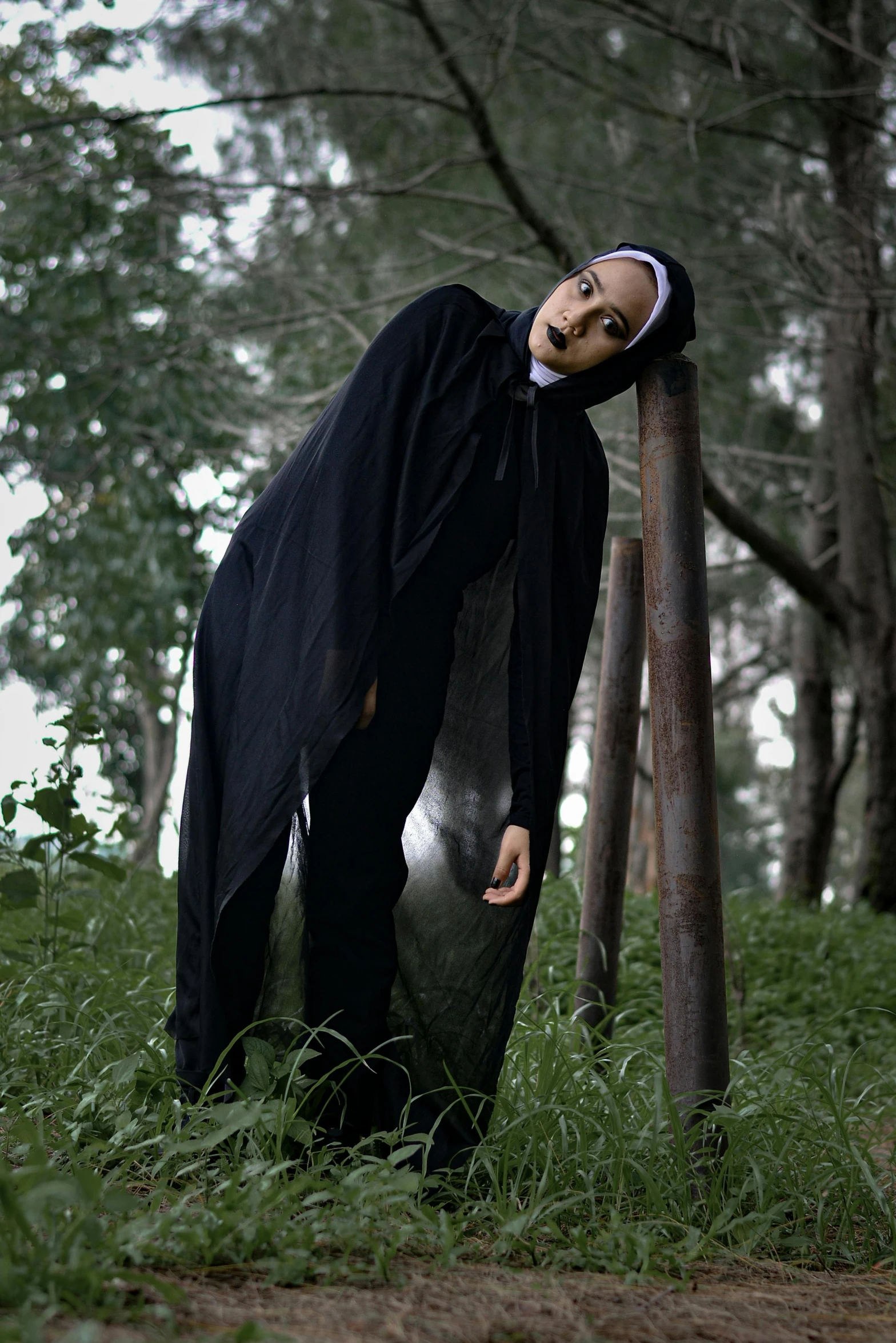 a creepy doll wearing a witches costume leaning on a tree trunk