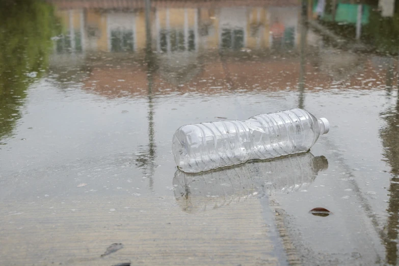 an empty bottle sits in the middle of a flooded street