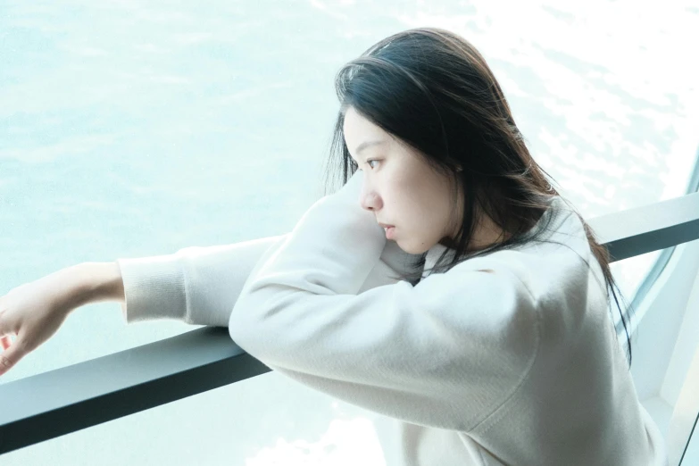 a woman leans out on the railing by the water