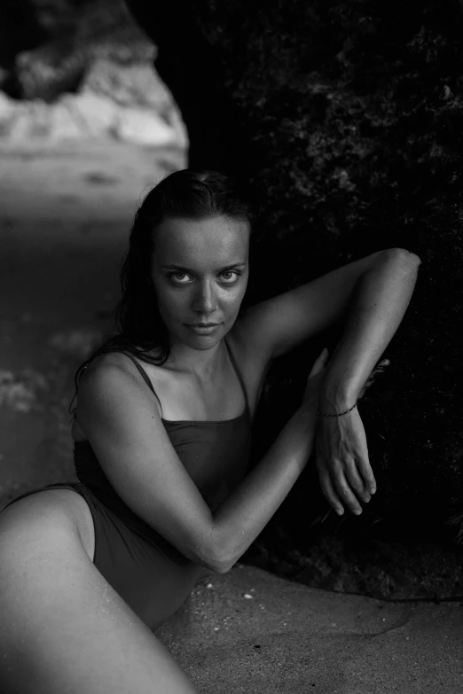 a beautiful woman in a swimsuit leaning on a rock