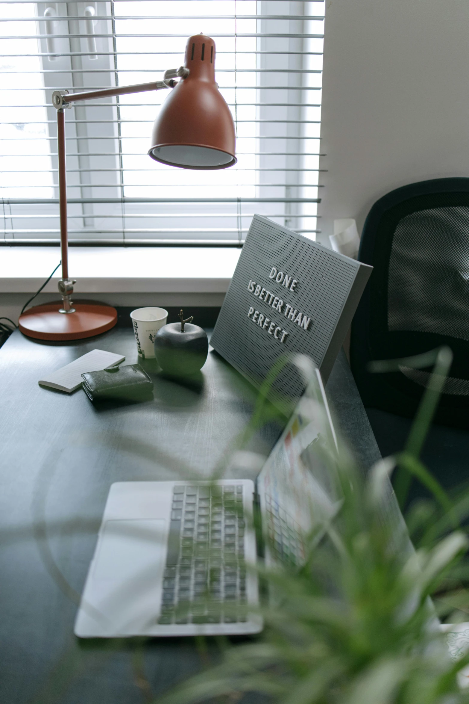 a table with a laptop and cup in front of a window