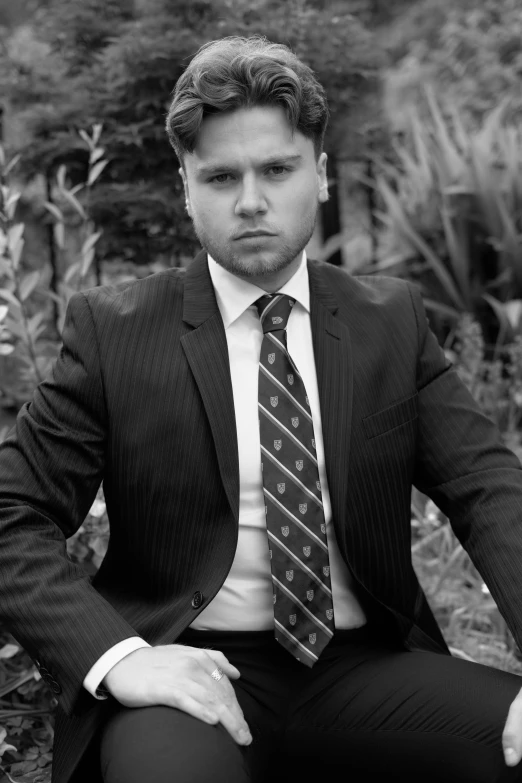 a man in a business suit sitting down wearing a tie