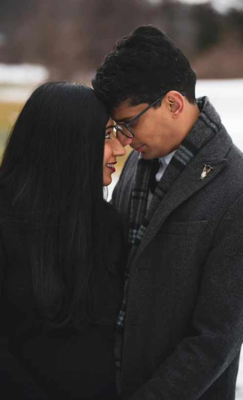 an asian couple stand close together in winter